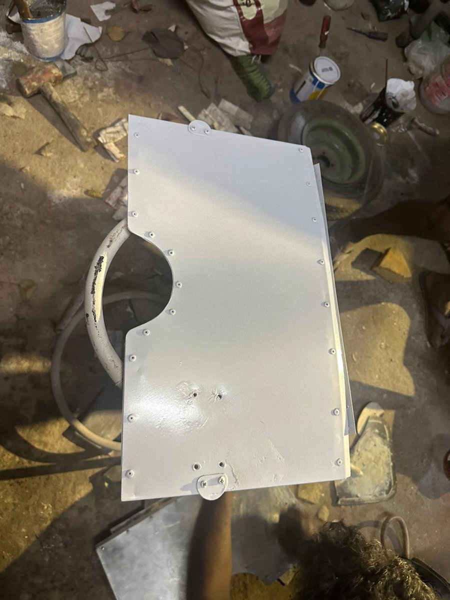White finished cowl-flap prototype on the workshop bench